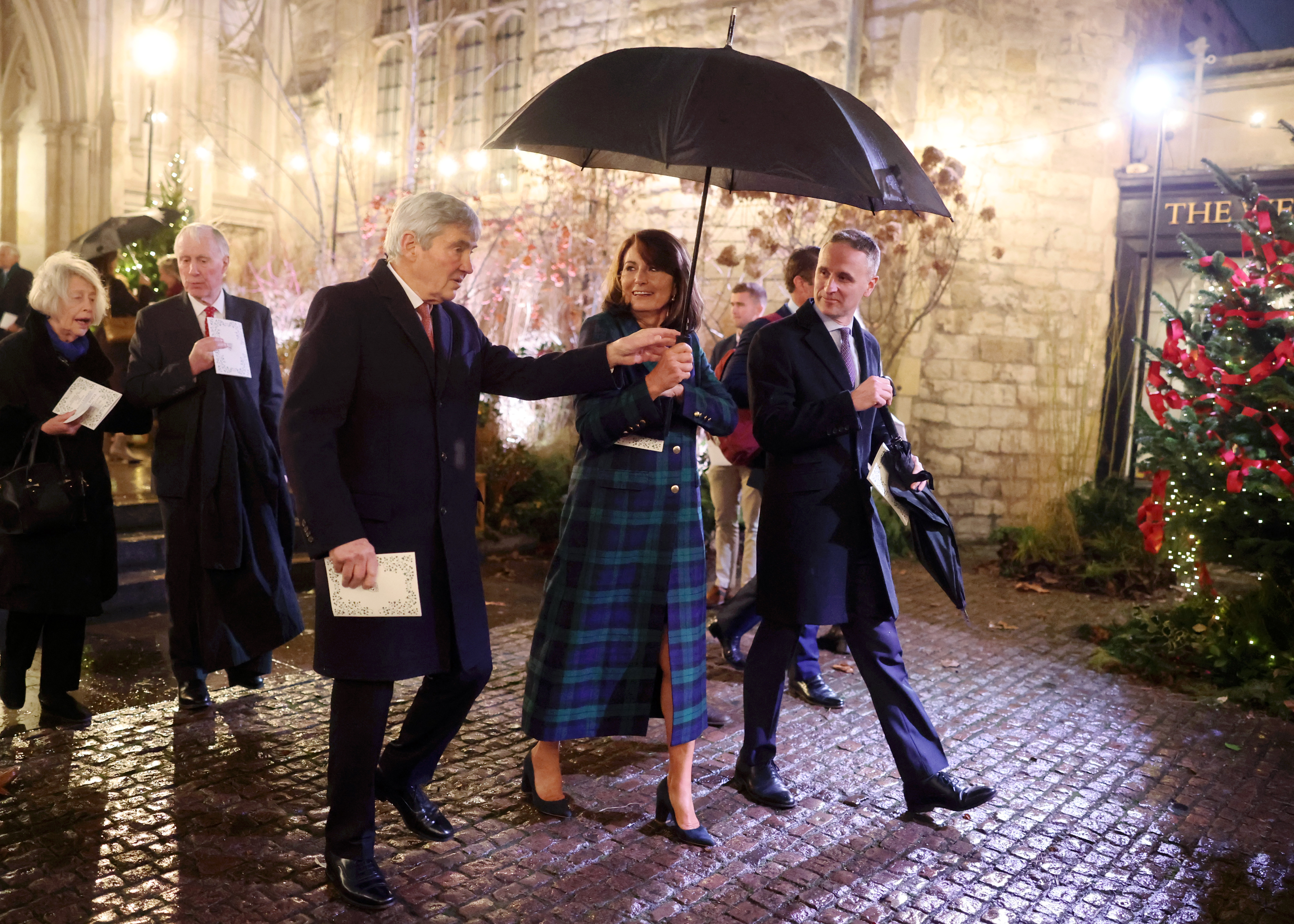 Carole Middleton y Michael Middleton caminan con un paraguas fuera de la Abadía de Westminster durante el evento navideño