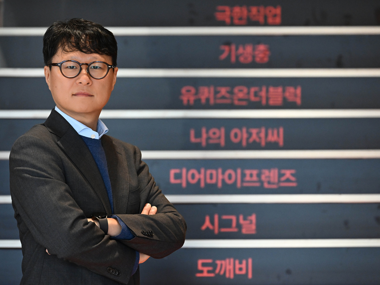 Yea Ju-yeol, jefe de la División de Artes Escénicas de CJ ENM, se encuentra frente a una escalera que muestra los nombres de los títulos más importantes de la compañía en el Centro CJ ENM en Sangam-dong, Mapo-gu, Seúl, el 3 de diciembre. (Lee Sang-sub/The Korea Herald)