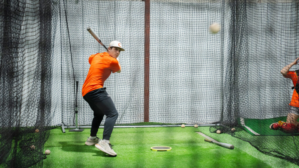 Un hombre con un bate de béisbol hace un swing en el gimnasio.